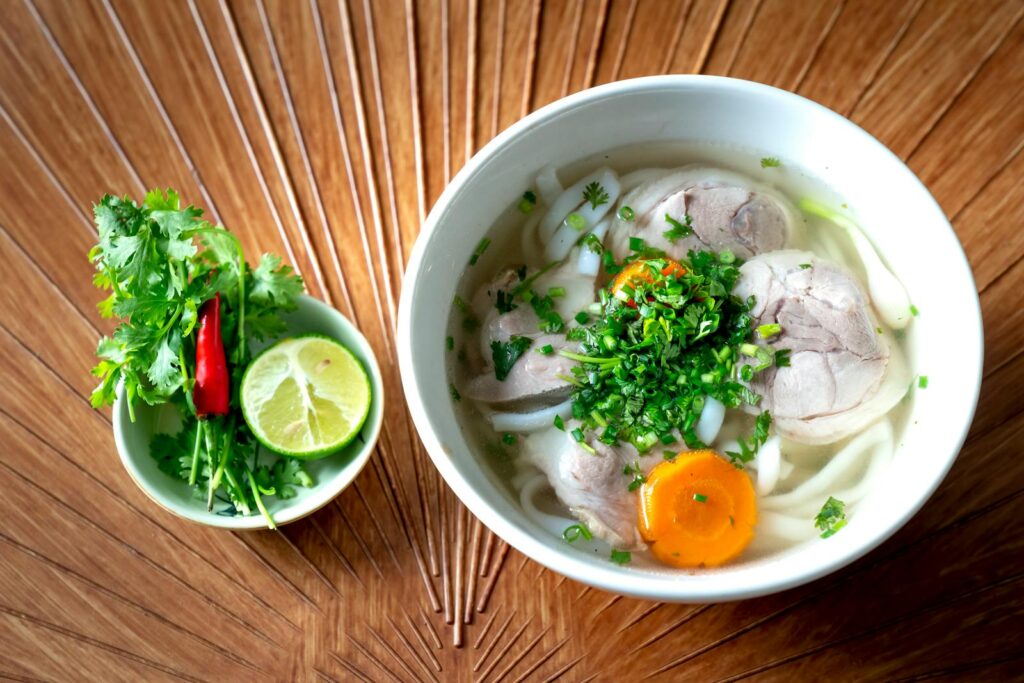 A vibrant bowl of Vietnamese Pho with fresh herbs and lime for a perfect meal.