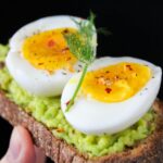 A delicious and healthy avocado toast topped with soft-boiled eggs, perfect for a nutritious breakfast.